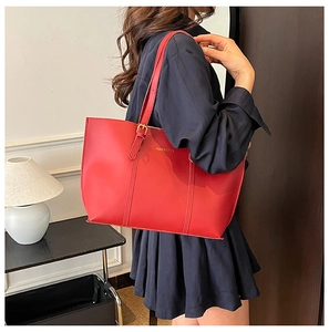 Detail of red leather tote bag with gold metal buckle and 'FASHION & BAGS' text