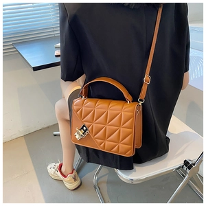 Détail d'un sac à main matelassé marron rétro avec fermoir doré sur un blazer noir