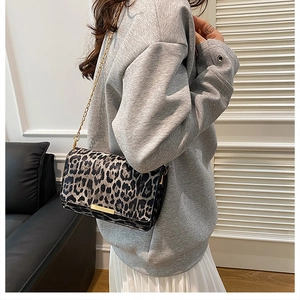 Detail of leopard print shoulder bag with gold chain strap worn with casual outfit