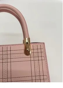 Dettaglio della borsa in pelle rosa con cuciture trapuntate e fibbia in metallo dorato lucido