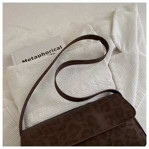 Close-up of vintage brown crossbody bag with animal print texture on corduroy background
