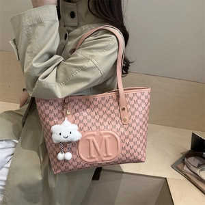 Pink tote bag with black M-letter print and plush cloud charm shown on model