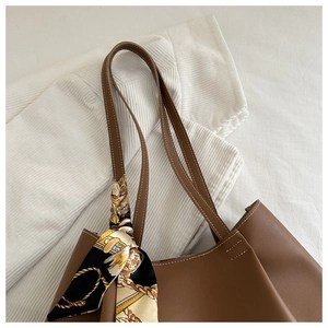 Détail d'un sac cabas en cuir marron avec surpiqûres blanches et foulard en soie décoratif