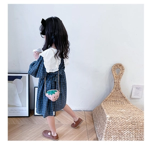 Dettaglio del retro di un abito a quadri per bambina con fiocco e borsa a fragola