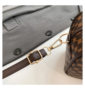 Close-up of golden hardware and adjustable leather strap on a vintage pattern bag