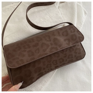 Close-up of dark brown suede baguette bag with leopard embossing on ribbed fabric