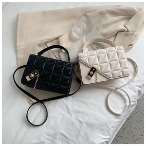 Détail de sacs bandoulière matelassés avec fermoirs en métal doré en noir et crème