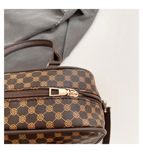 Detailed close-up of dark brown textured leather bag with gold four-leaf clover patterns