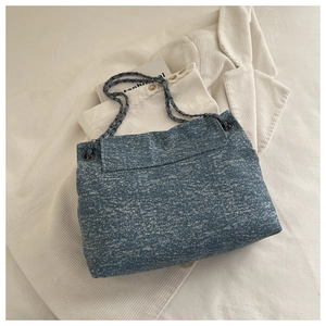 Gros plan du sac fourre-tout en denim avec bandoulière chaîne et texture flocon bleue
