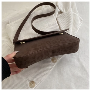 Macro view of leopard print suede texture and golden metal buckle on retro baguette bag