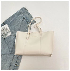 Detail of a beige tote bag showing high-quality leather texture and metallic buckle