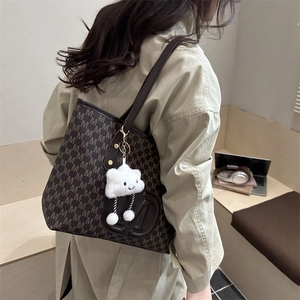 Detail of dark brown monogram tote bag with large M logo and white cloud charm