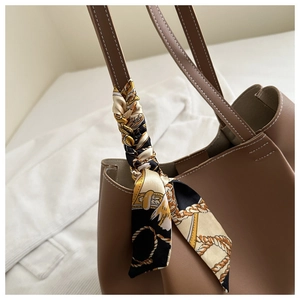 Détail d'un sac cabas marron avec un foulard en soie baroque décoratif sur la poignée