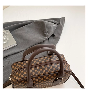 Macro shot of retro dark brown boston bag with classic geometric pattern and leather handles