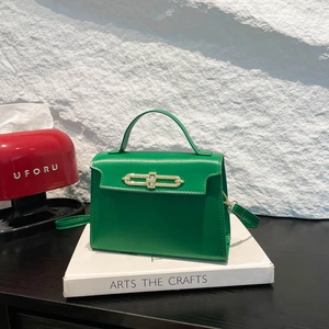 Elegant bright green leather handbag with golden buckle on textured white background