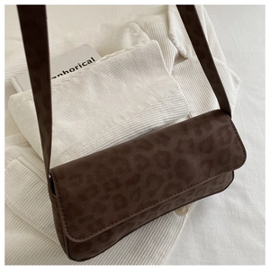 Close-up of vintage leopard print baguette bag with textured suede finish on white fabric