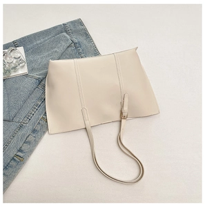 Flat lay of a beige tote bag with adjustable strap on white textured surface