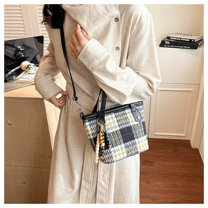 Detail of vintage plaid tote bag with wooden bead charm and elegant leather handles