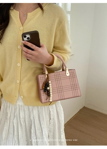 Dettaglio borsa tote rosa in pelle opaca con ciondolo di perline colorate e fibbie dorate