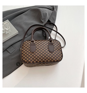 Detail view of a vintage brown leather satchel with geometric patterns and shoulder strap