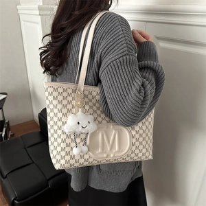 Detailed view of cream tote bag featuring letter embossing and a cute cloud charm
