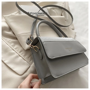 Close-up of grey square bag showing sequin patchwork detail and golden logo on the flap