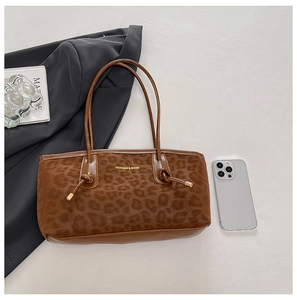 Detail of leopard print tote bag with gold logo and knotted strap on gray background