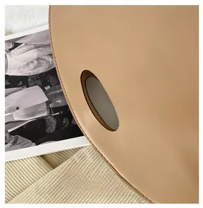 Detail of light brown leather handbag with unique circular cutout handle and stitching