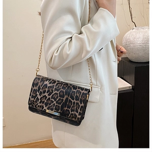 Minimalist leopard print shoulder bag with gold chain strap worn over a white blazer