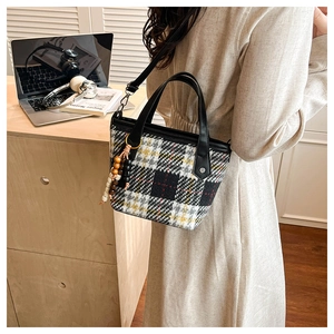 Détail du sac cabas à carreaux en tweed avec poignées en cuir noir et breloque en bois