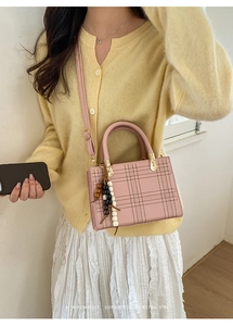 Borsa a tracolla retrò rosa con motivo a griglia e ciondolo in legno su modella