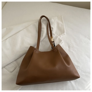 Détail du sac cabas en cuir marron avec surpiqûres et foulard décoratif en soie imprimé