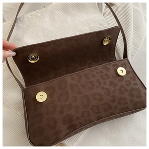 Detail view of leopard print baguette bag featuring dual gold magnetic closures