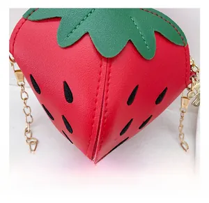 Dettaglio della borsa a fragola con texture in ecopelle e tracolla a catena dorata