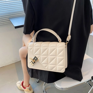Sac à bandoulière matelassé beige chic avec boucle dorée porté par un mannequin