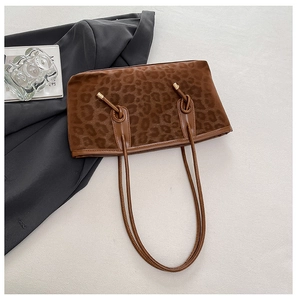 Detail of leopard print tote bag with soft suede texture and leather handles on grey suit