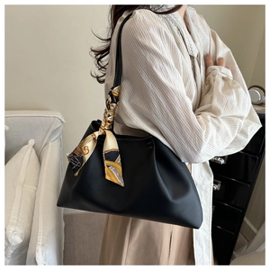 Détail d'un sac à main plissé noir avec une décoration de poignée en foulard de soie chic