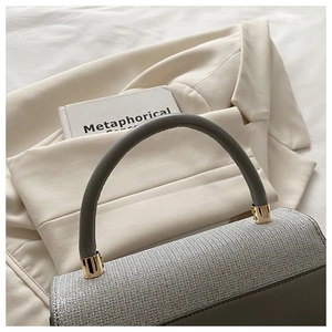Detailed shot of sparkling silver sequins and gray leather handle with gold hardware