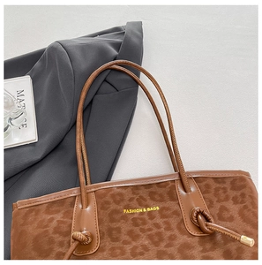 Detail of leopard print tote bag with gold lettering and stylish knotted leather strap