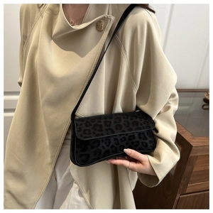 Detail of vintage black leopard texture shoulder bag styled with a beige trench coat