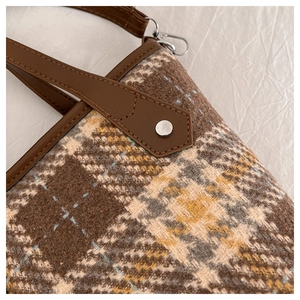 Gros plan du sac cabas à carreaux marron avec lanière en cuir et rivet argenté