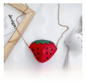 Dettaglio della borsa a tracolla a forma di fragola con foglia verde e catena d'oro