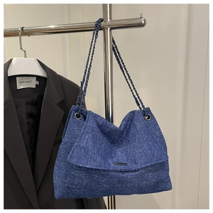 Détail du sac bandoulière en denim bleu avec chaînes argentées et boucle métallique