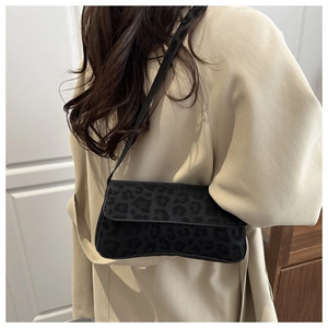 Close-up of a black leopard print underarm bag worn by a model in a beige coat