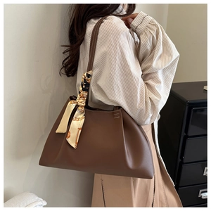 Détail du sac cabas en cuir marron café avec un foulard en soie texturé sur l'anse