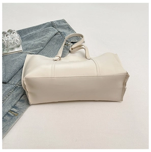 Detail of minimalist cream tote bag showing durable double stitching and wide base structure
