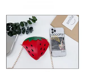 Confronto dimensioni di una borsa a tracolla a forma di fragola con catena