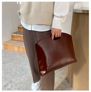 Detail of dark brown leather tote bag with unique cutout handle and minimalist design