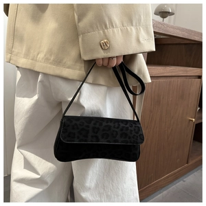 Detail of vintage black leopard print baguette bag with soft velvet texture and carry strap