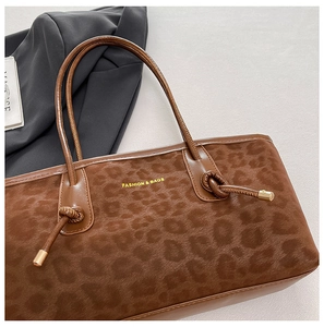 Macro detail of leopard print tote bag featuring golden lettering and woven knot handle
